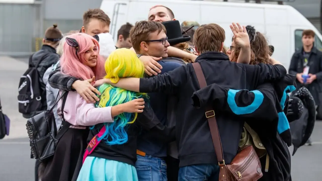 Grupa fanów w kolorowych perukach i strojach przytula się na Pyrkonie w Poznaniu.