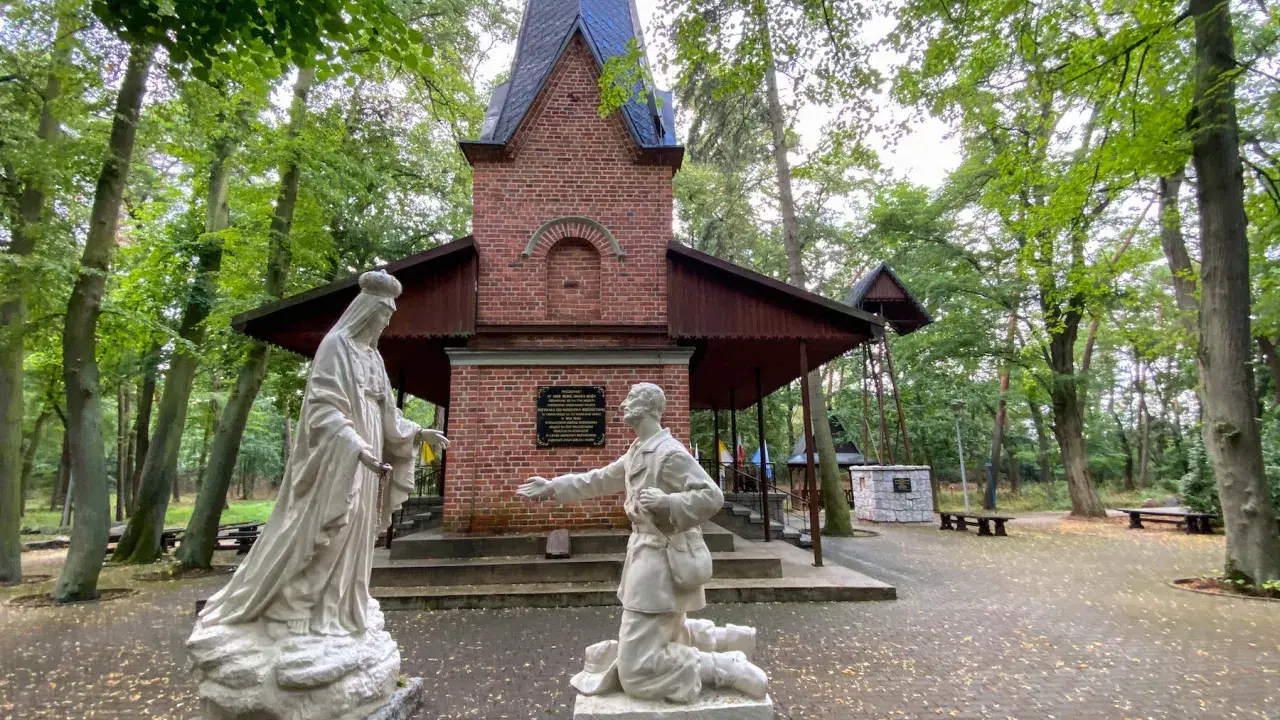 Rzeźby przed bazyliką w Licheniu: klęczący mężczyzna i Matka Boża.