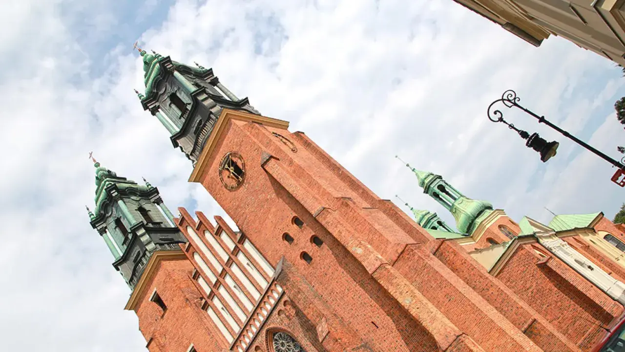Majestatyczna katedra na Ostrowie Tumskim, z ceglanymi wieżami i zielonymi kopułami, góruje nad niebem.