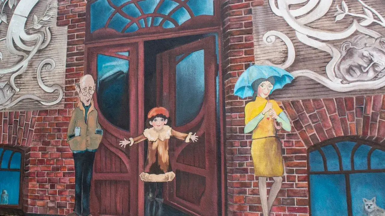 Urocze murale w Poznaniu: starszy pan z kubkiem, dziecko w drzwiach i kobieta z parasolką.