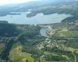 Widok z lotu ptaka na zaporę wodną i rozległy zbiornik, jeden z najpiękniejszych jezior w Polsce. Otoczone lasami, z malowniczymi wioskami.