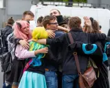 Grupa fanów w kolorowych perukach i strojach przytula się na Pyrkonie w Poznaniu.