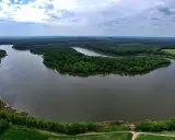Malowniczy krajobraz z jeziorem, lasami i polami. W oddali widać wyspę konwaliową, otoczoną zielenią.