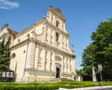 Jasny kościół Karmelitów w Poznaniu z zielenią i błękitnym niebem.