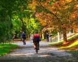 Kalisz wydarzenia weekend: ludzie jeżdżą na rowerach i spacerują alejkami parku w jesiennym słońcu.