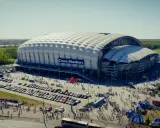 Enea Stadion z lotu ptaka, otoczony parkingami i tłumem ludzi.