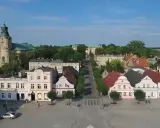 Rydzyna atrakcje: malowniczy rynek z kolorowymi kamieniczkami, kościołem i pałacem w tle.