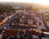 Widok z lotu ptaka na szamotuły rynek z kolorowymi kamienicami i ulicami oświetlonymi zachodzącym słońcem.