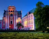 Piękna poznańska trasa spacerowa z zabytkowymi budynkami oświetlonymi wieczorem i bujną zielenią.