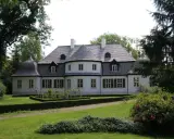 Malowniczy dwór w Koszutach otoczony zielenią. Klasyczna architektura z wieżyczkami i mansardowym dachem.