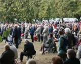 Tłum ludzi zgromadzony na trawie, drzewa w tle. Odpust w Bieniszewie przyciągnął wielu wiernych.