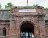 Wejście do Fortu Graf-Kirchbach, historycznej twierdzy w Poznaniu. Grupa turystów wchodzi do ciemnego tunelu.