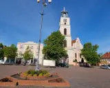 Rynek w Chodzieży Wielkopolskiej z kościołem i kamienicami. Słoneczny dzień, błękitne niebo.
