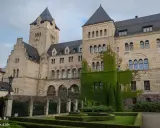 Imponujące zamki w Poznaniu, z kamienną fasadą i zielonym bluszczem, otoczone zadbanym ogrodem.