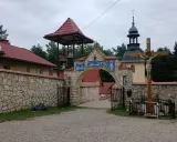 Kamienny łuk z mozaikami i dzwonnicą prowadzi do klasztoru, jednego z wielu pustelni w Polsce. Obok krzyż z Jezusem.