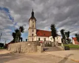 Kamienna górka duchowna z kościołem i wieżą na tle burzowych chmur.