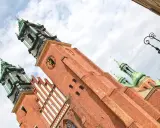 Majestatyczna katedra na Ostrowie Tumskim, z ceglanymi wieżami i zielonymi kopułami, góruje nad niebem.