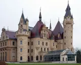 Imponujący zamek z licznymi wieżami i czerwonymi dachami. Idealne miejsce na zwiedzanie zamków i pałaców.