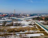 Zimowy krajobraz z nowoczesnymi mostami berdychowskimi, rzeką i panoramą miasta w tle.