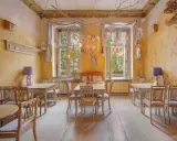 Przytulne wnętrze kawiarni Ptasie Radio Poznań. Drewniane stoły i krzesła z motywami ptaków, ozdobne ściany i wiszące dekoracje tworzą magiczną atmosferę.