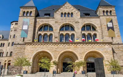 Kamienny pałac cesarski z łukowymi oknami i wieżyczkami. Na fasadzie flagi i banery informujące o Centrum Kultury Zamek i kinie pałacowym.