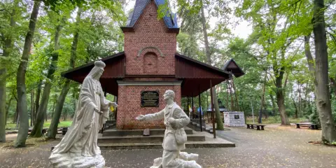 Rzeźby przed bazyliką w Licheniu: klęczący mężczyzna i Matka Boża.