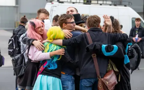 Grupa fanów w kolorowych perukach i strojach przytula się na Pyrkonie w Poznaniu.
