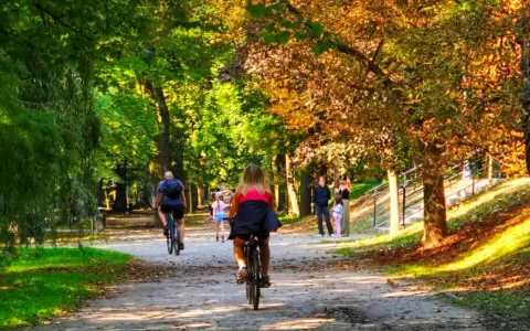 Kalisz wydarzenia weekend: ludzie jeżdżą na rowerach i spacerują alejkami parku w jesiennym słońcu.
