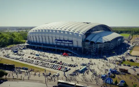 Enea Stadion z lotu ptaka, otoczony parkingami i tłumem ludzi.