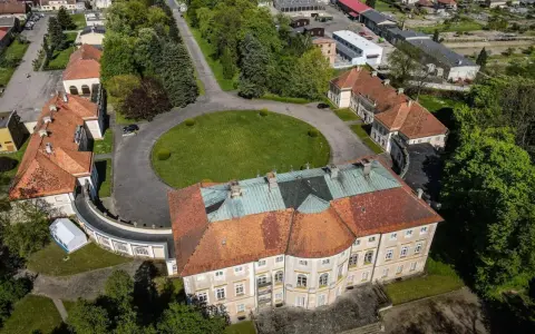 Pałac w Pawłowicach z lotu ptaka, otoczony zielenią i innymi budynkami.