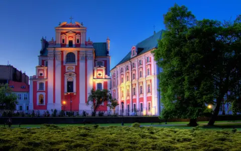 Piękna poznańska trasa spacerowa z zabytkowymi budynkami oświetlonymi wieczorem i bujną zielenią.