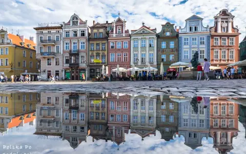 Kolorowe kamienice na Starym Rynku w Poznaniu odbijają się w kałuży. W tle widać ludzi i ogródki kawiarniane. Poznań Jeżyce to urokliwe miejsce.
