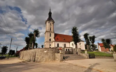Kamienna górka duchowna z kościołem i wieżą na tle burzowych chmur.