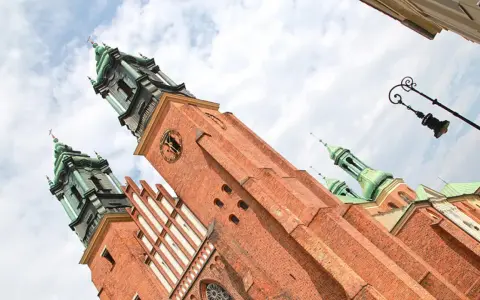 Majestatyczna katedra na Ostrowie Tumskim, z ceglanymi wieżami i zielonymi kopułami, góruje nad niebem.