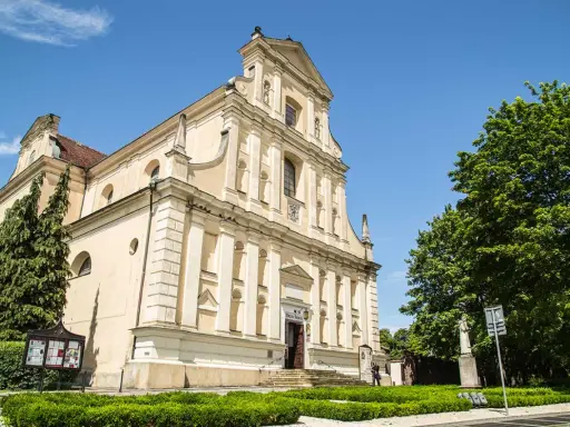 Jasny kościół Karmelitów w Poznaniu z zielenią i błękitnym niebem.