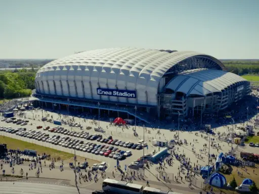 Enea Stadion z lotu ptaka, otoczony parkingami i tłumem ludzi.
