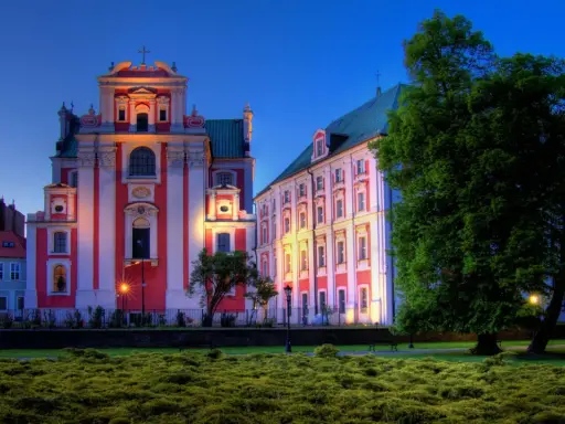 Piękna poznańska trasa spacerowa z zabytkowymi budynkami oświetlonymi wieczorem i bujną zielenią.