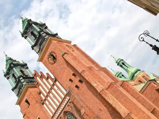 Majestatyczna katedra na Ostrowie Tumskim, z ceglanymi wieżami i zielonymi kopułami, góruje nad niebem.