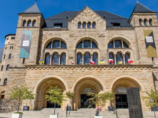 Kamienny pałac cesarski z łukowymi oknami i wieżyczkami. Na fasadzie flagi i banery informujące o Centrum Kultury Zamek i kinie pałacowym.