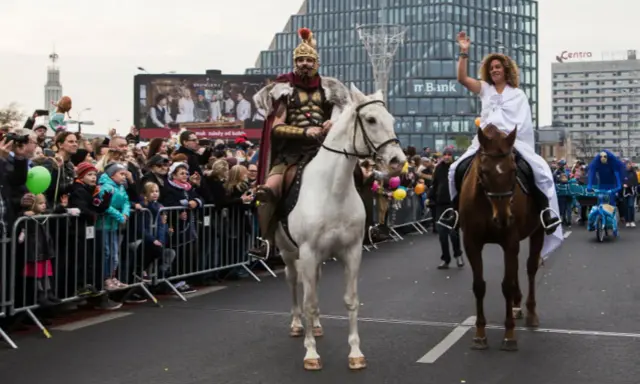 Kiedy jest Marcina, rzymski wojownik na białym koniu i kobieta w bieli na brązowym koniu przejeżdżają przez tłum.