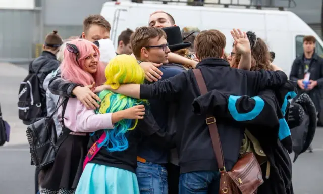 Grupa fanów w kolorowych perukach i strojach przytula się na Pyrkonie w Poznaniu.