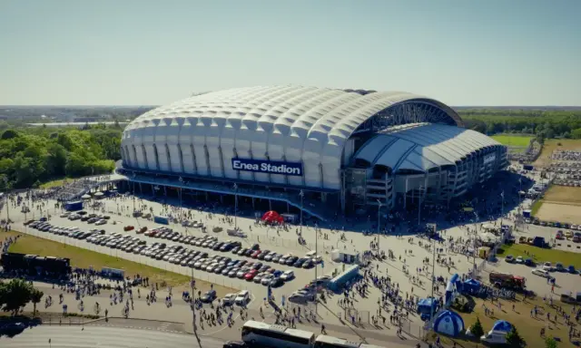 Enea Stadion z lotu ptaka, otoczony parkingami i tłumem ludzi.