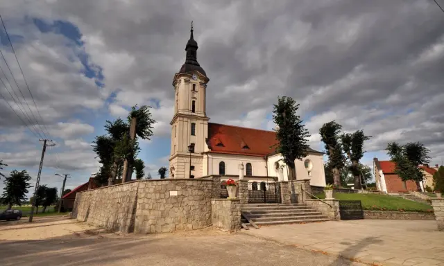 Kamienna górka duchowna z kościołem i wieżą na tle burzowych chmur.