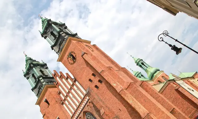 Majestatyczna katedra na Ostrowie Tumskim, z ceglanymi wieżami i zielonymi kopułami, góruje nad niebem.