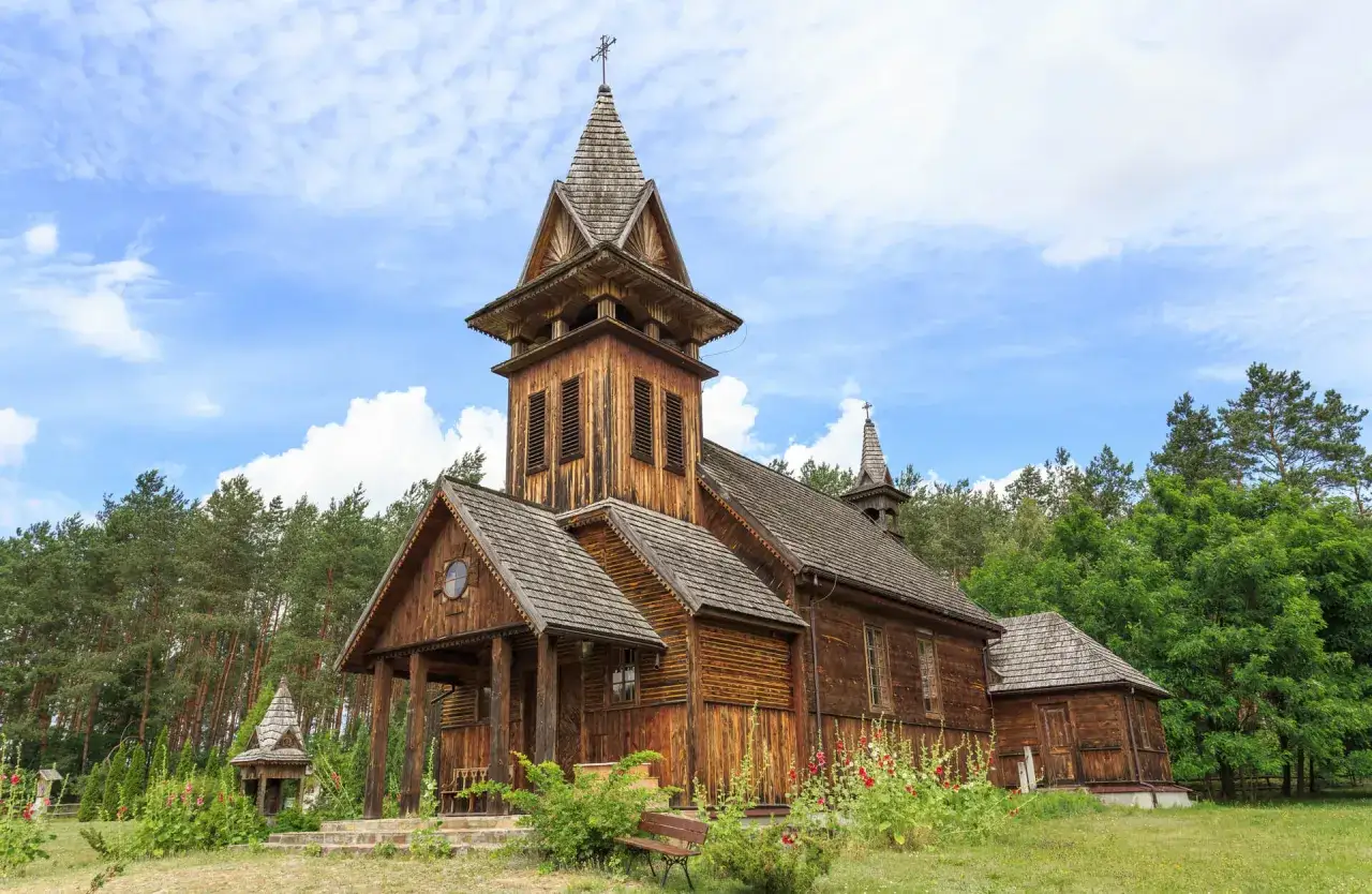 Piękny, drewniany kości&oacute;ł w Polsce, otoczony zielenią.