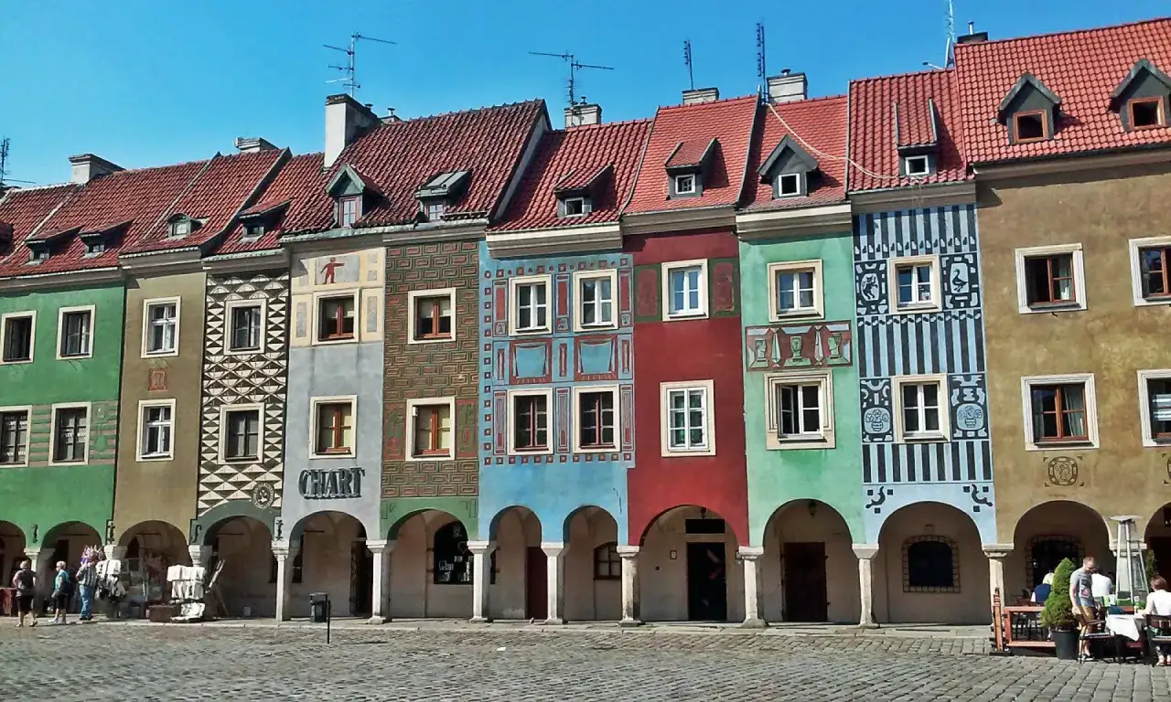 Kolorowe kamienice na Starym Rynku w Poznaniu, przykład secesji w Poznaniu, z arkadami i brukowanym placem.