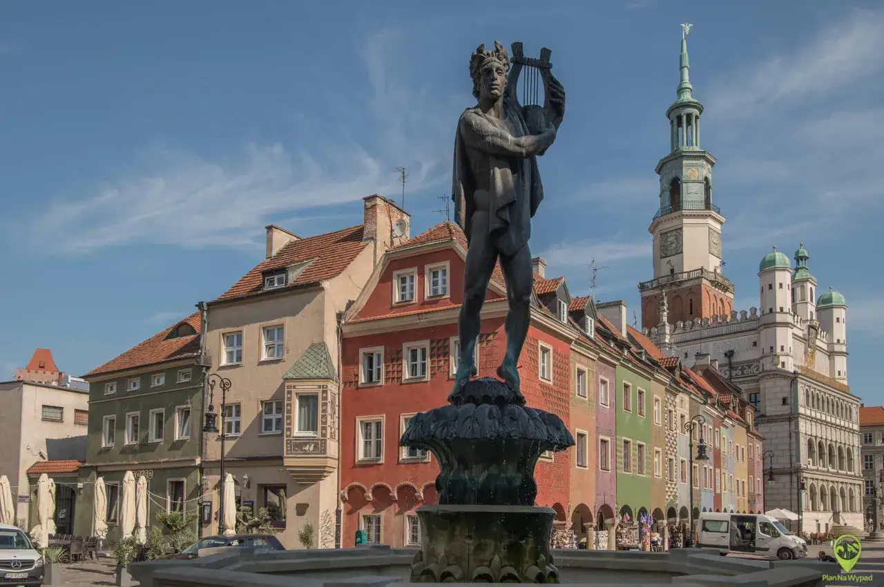 Fontanna z Apollinem na Rynku w Poznaniu, idealne miejsce na poznań na weekend. Kolorowe kamieniczki i ratusz w tle tworzą malowniczy widok.