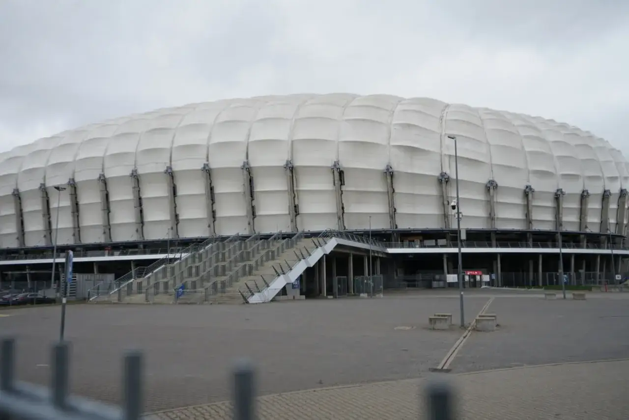 Enea Stadion z białym, falistym dachem i betonowymi schodami prowadzącymi do wejścia.