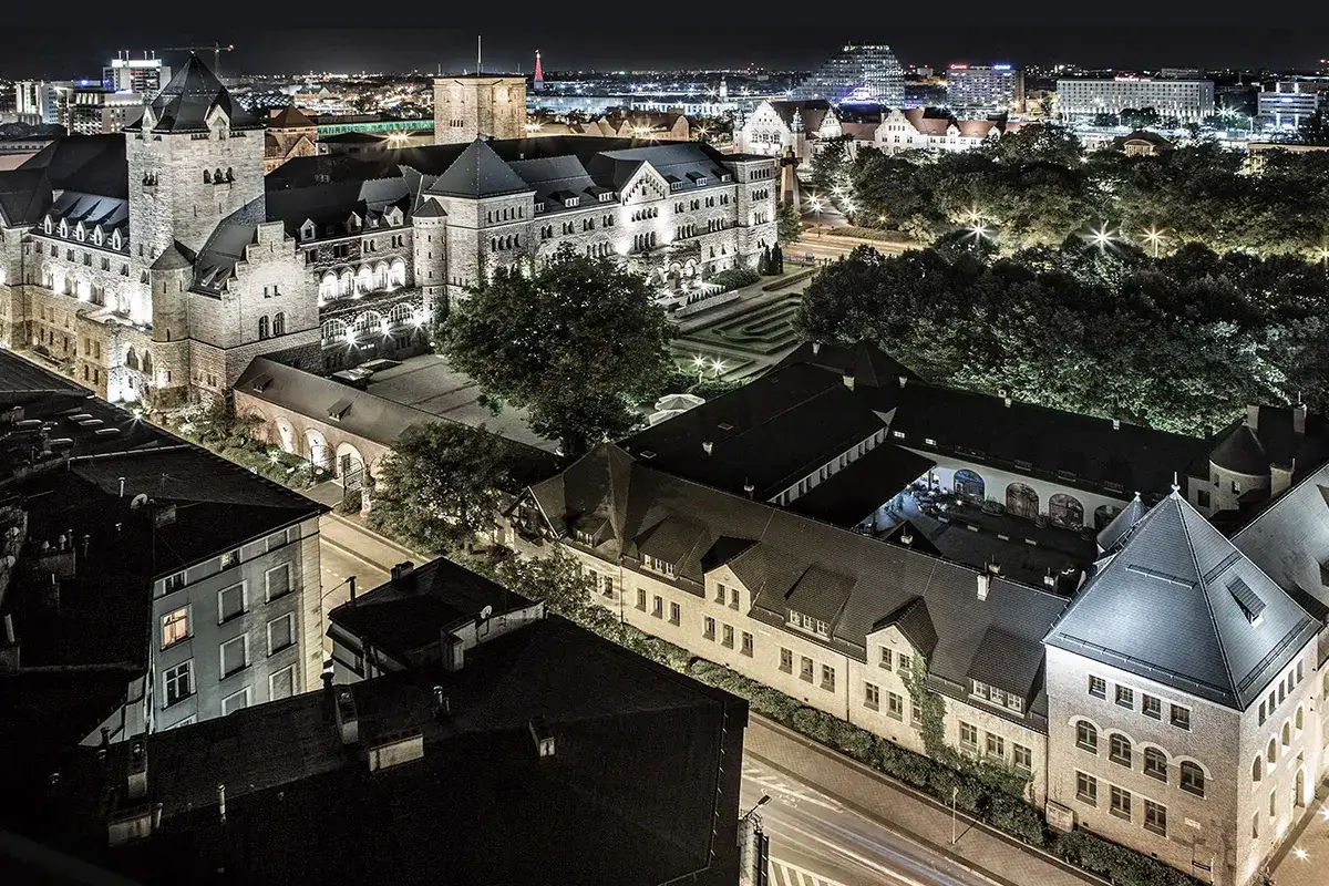 Nocny widok na imponujące zamki w Poznaniu, oświetlone i otoczone miejskim krajobrazem.
