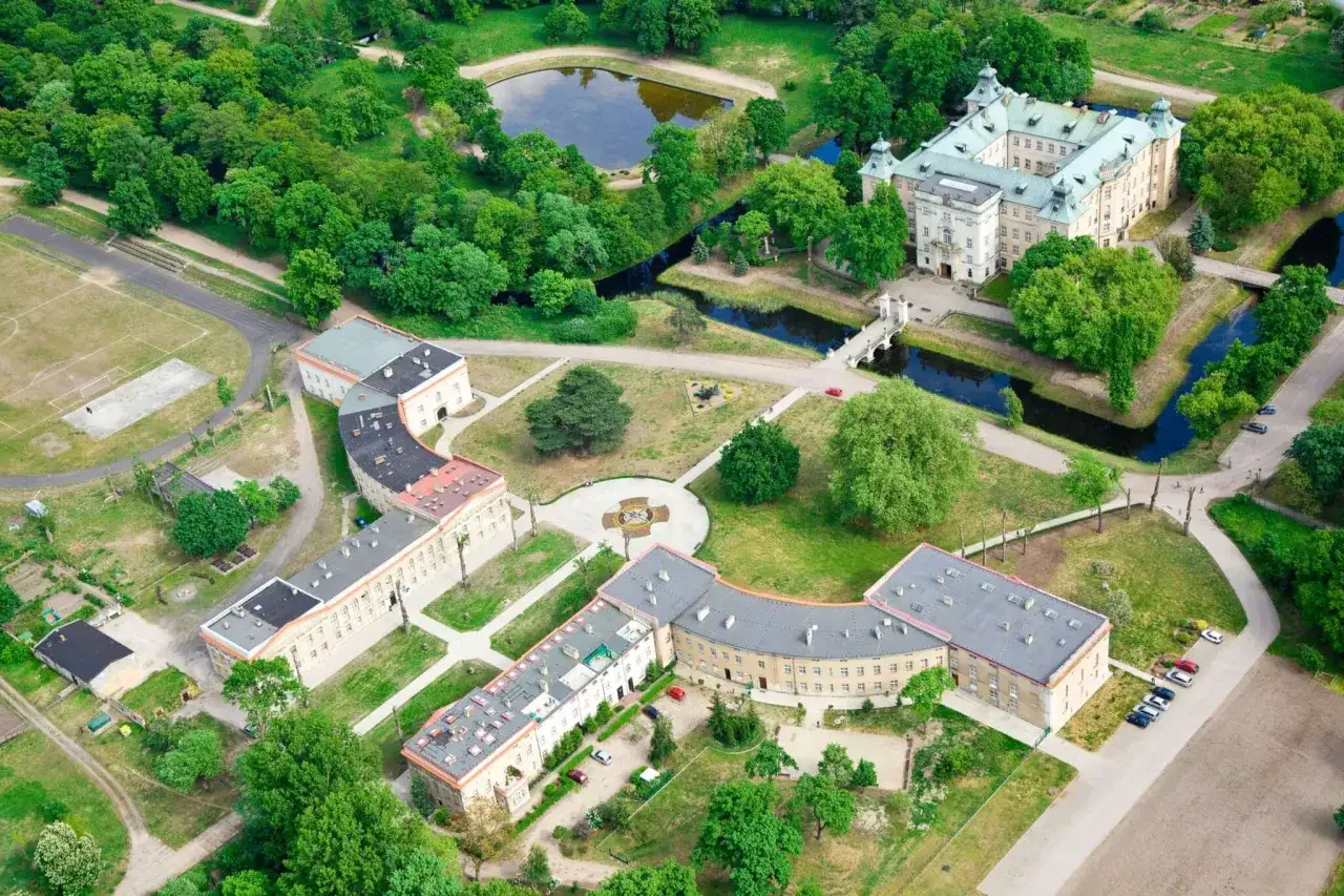 Największy zamek w Wielkopolsce, otoczony fosą i parkiem, z rozległymi budynkami i dziedzińcami.